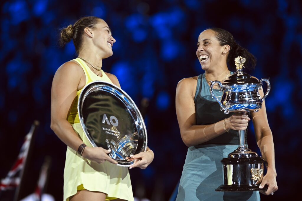 2025 Australian Open runner-up Aryna Sabalenka smiles at champion Madison Keys while holding their hardware.