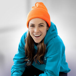 Sports Are Fun! host and soccer icon Kelley O'Hara poses in a blue hoodie and orange cap.