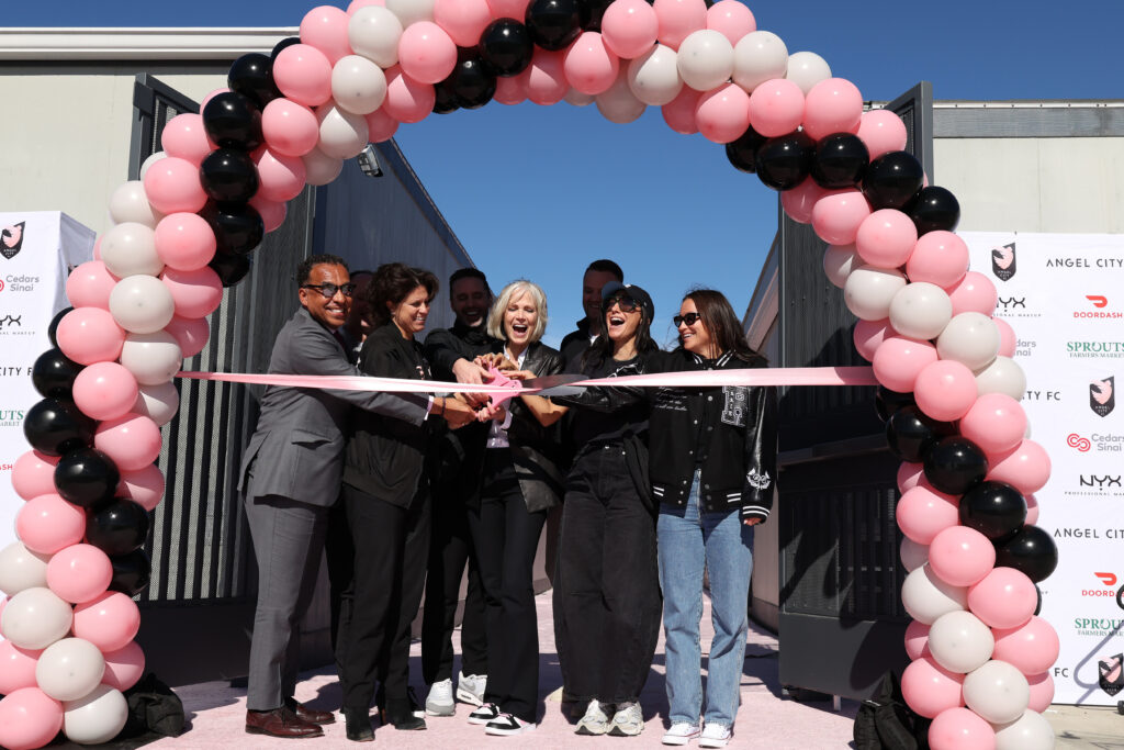 Angel City leaders like forward Christen Press and captain Ali Riley surround owner Willow Bay as she cuts the ribbon on ACFC's new Performance Center.