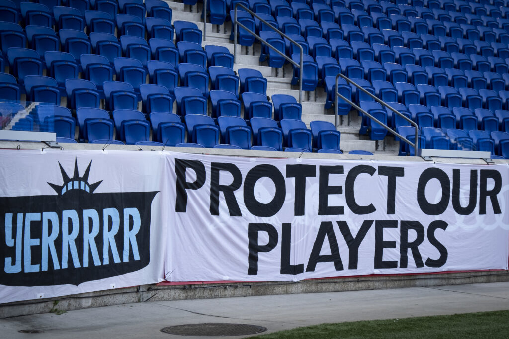 A Gotham FC banner reads "Protect Our Players" before a 2021 NWSL match.