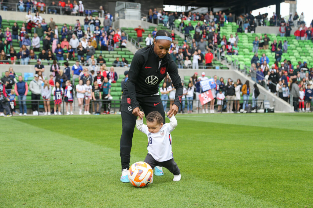 USWNT star Crystal Dunn helps her son, Marcel, kick a ball on the pitch after an international friendly.