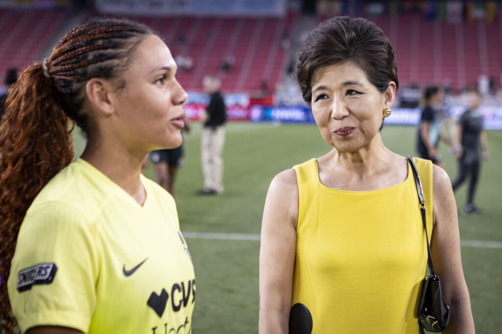 Washington Spirit owner Michele Kang listens to star forward Trinity Rodman speak.