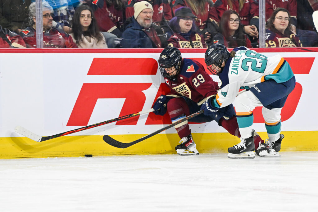 Montréal's Marie-Philip Poulin battles New York's Micah Zandee-Hart for the puck along the boards during a December 2024 PHWL game.