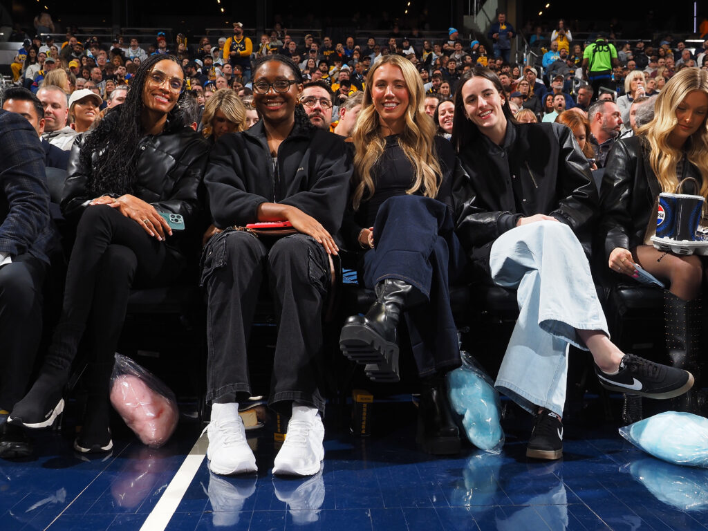 Indiana Fever players DeWanna Bonner, Aliyah Boston, Lexie Hull, and Caitlin Clark attend an NBA game.