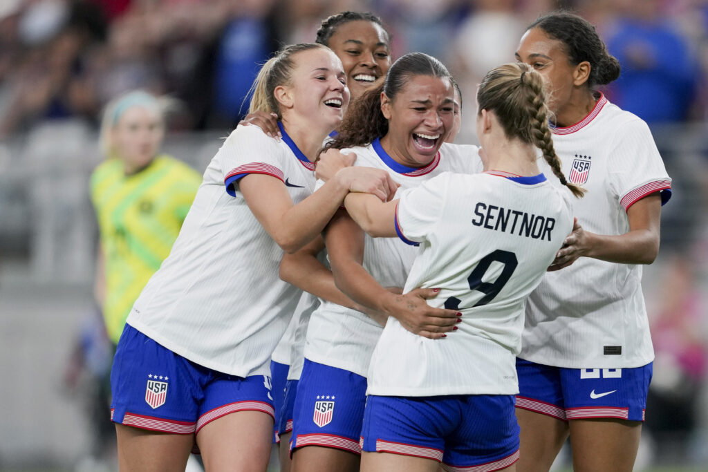 Michelle Cooper celebrates her first international goal with her USWNT teammates.