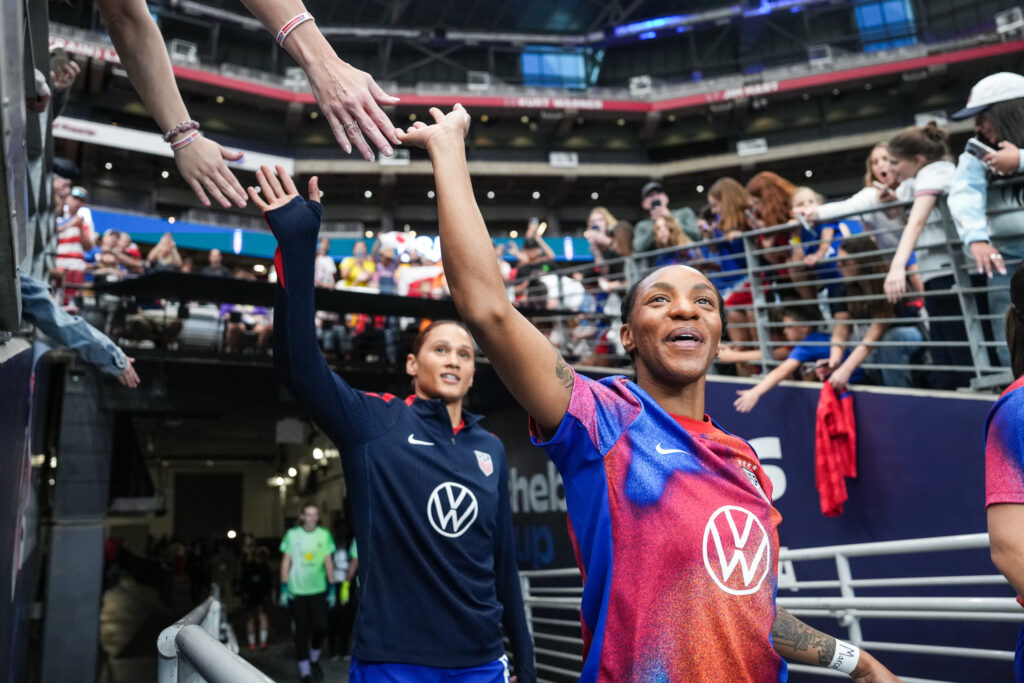 USWNT stars Crystal Dunn and Lynn Biyendolo greet fans as they enter the pitch before a 2025 SheBelieves Cup match.