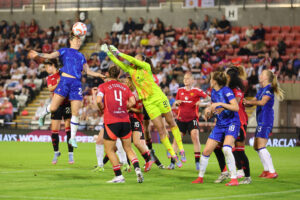 Chelsea defender Lucy Bronze heads the game-winning goal past Manchester United goalkeeper Phallon Tullis-Joyce in a 2025 WSL match.