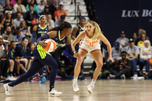 Connecticut's Jacy Sheldon defends Dallas's Arike Ogunbowale during the Wings' first 2025 WNBA season victory.