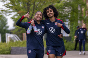 Catarina Macario and Lily Yohannes smile and pose as they walk into a USWNT training session.