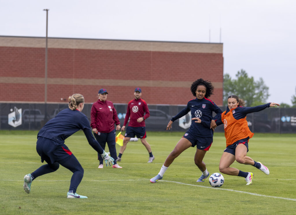 First-time USWNT call-up Kerry Abello defends Lily Yohannes while head coach Emma Hayes watches during training camp.