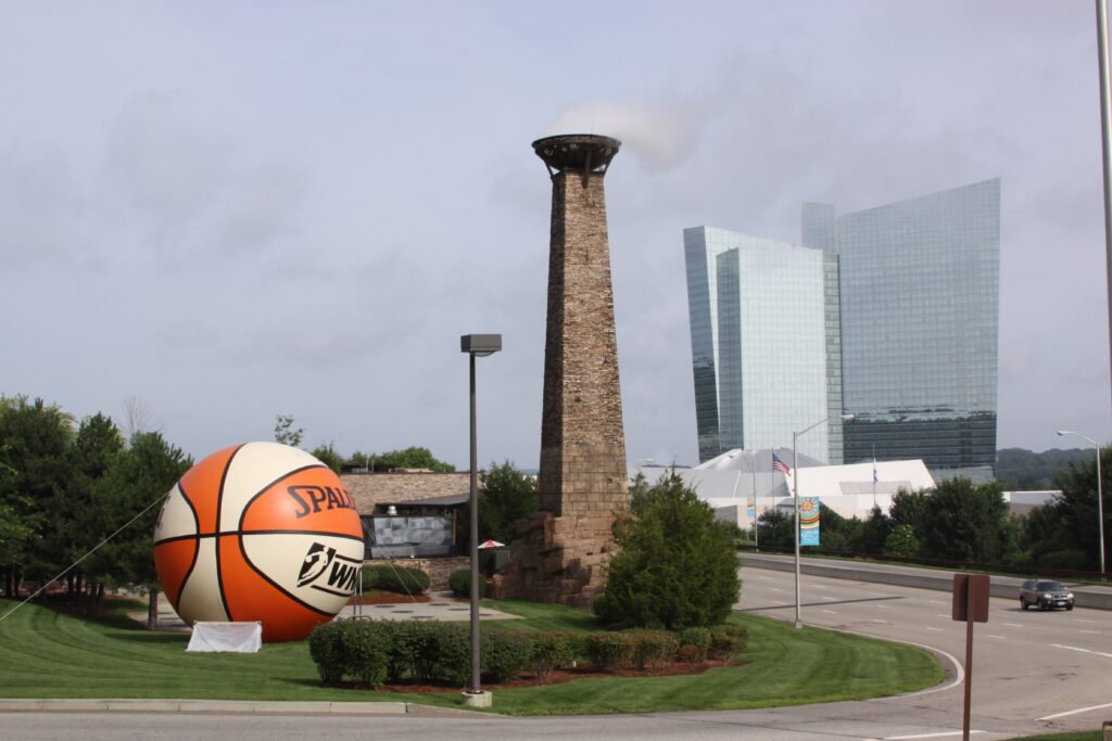 An exterior view of the Mohegan Sun hotel in Uncasville, Connecticut, with a large inflated WNBA basketball in front.