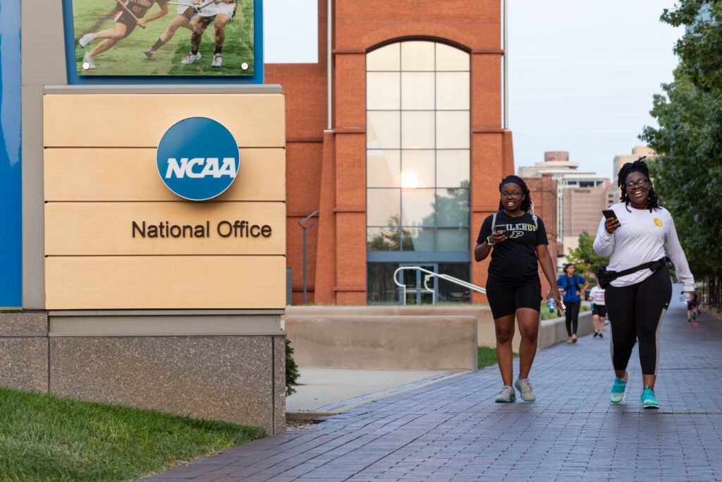 Two students walk by the exterior of the NCAA National Office in Indianapolis, Indiana.