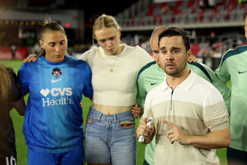 Washington Spirit head coach Jonatan Giráldez talks with the team after a 2025 NWSL match.