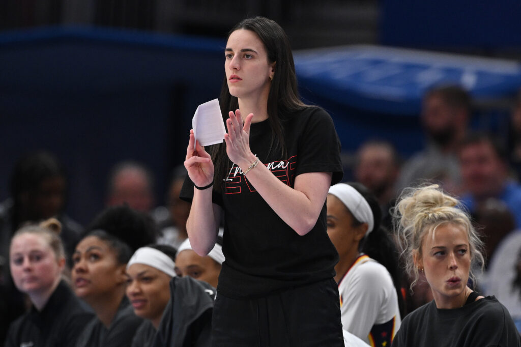 Injured Indiana Fever star Caitlin Clark cheers on her team from the sidelines during a 2025 WNBA game.