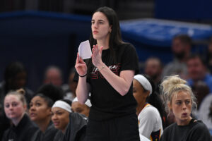 Injured Indiana Fever star Caitlin Clark cheers on her team from the sidelines during a 2025 WNBA game.