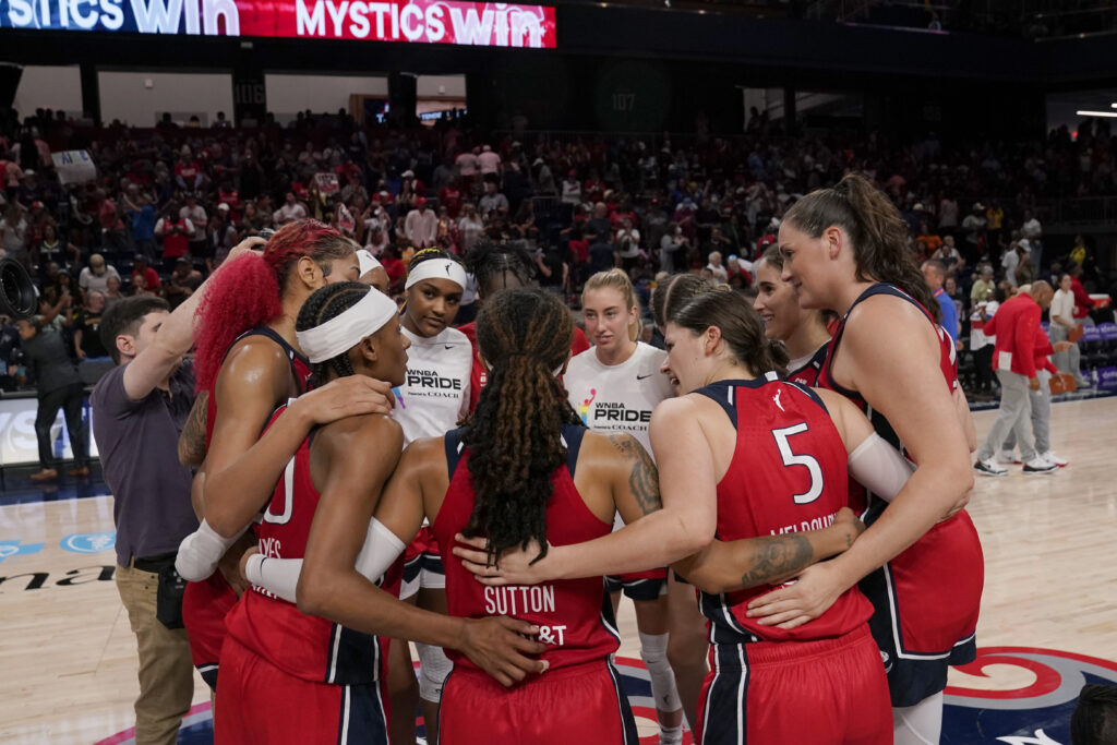Washington Mystics players celebrate together in a huddle after winning in overtime against the Dallas Wings at Carefirst Arena on June 22, 2025 in Washington, DC. 
