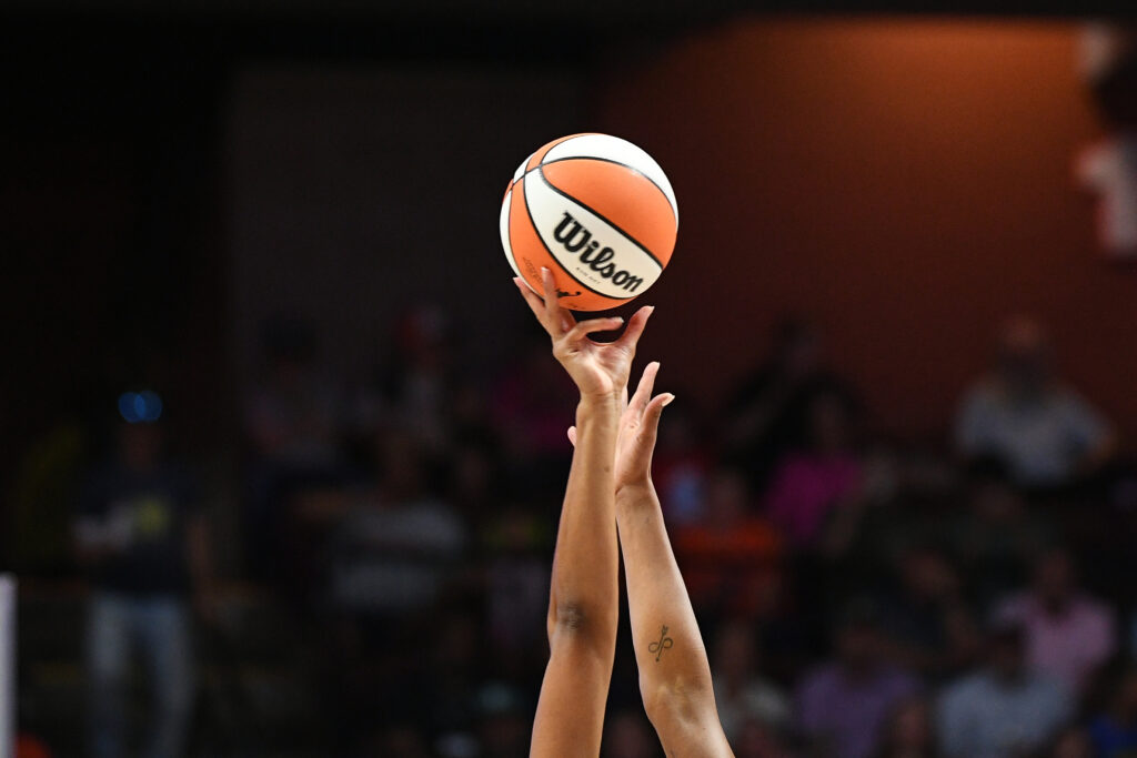 Hands reach for the basketball as a 2025 WNBA game tips off.