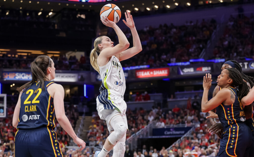 Dallas Wings rookie Paige Bueckers shoots the ball as Indiana Fever guard Caitlin Clark watches during a 2025 WNBA game.
