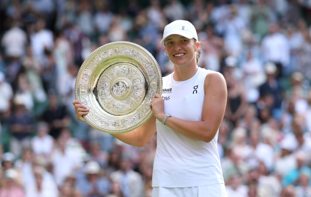 Iga Świątek poses holding her 2025 Wimbledon trophy.