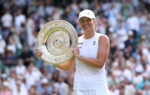 Iga Świątek poses holding her 2025 Wimbledon trophy.