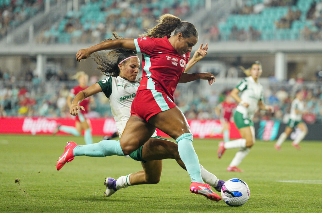 Palmeiras's Gaby Santos tries to slide tackle Kansas City attacker Michelle Cooper as she dribbles the ball during a 2025 Teal Rising Cup semifinal.