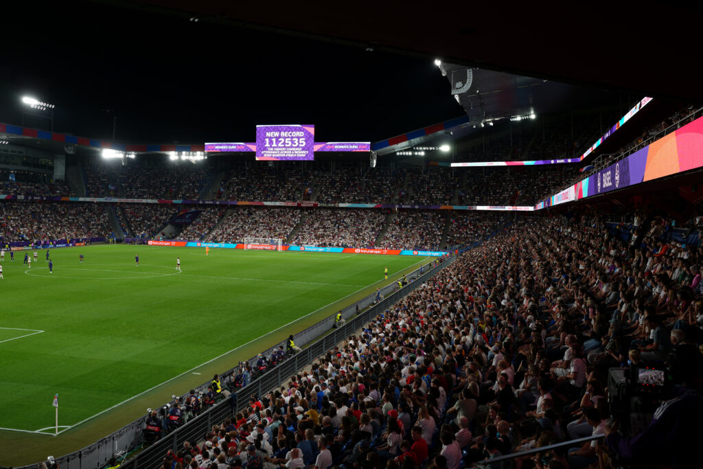 A screen over the pitch reads "New Record 112,535, the highest combined attendance across a women's Euro quarterfinals stage" during a 2025 Euro match.