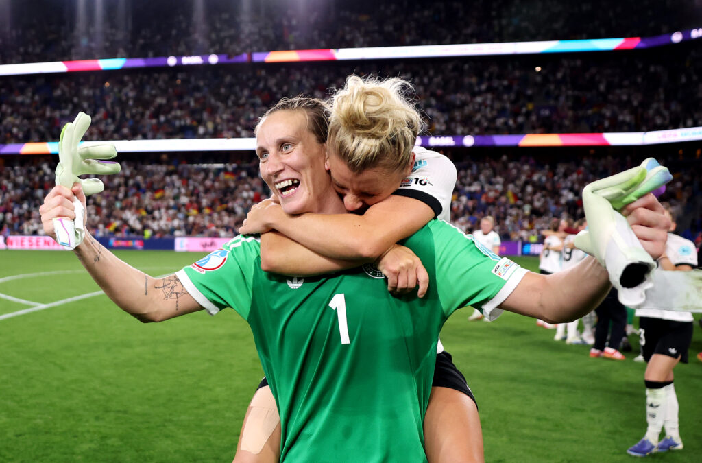 Germany's Linda Dallmann hugs goalkeeper Ann-Katrin Berger after winning their 2025 Euro quarterfinal on penalty kicks.