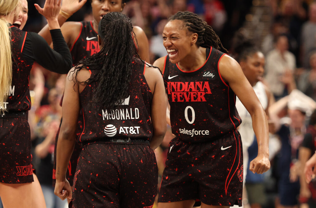 Indiana Fever guard Kelsey Mitchell celebrates teammate Aari McDonald's three-pointer during a 2025 WNBA game.