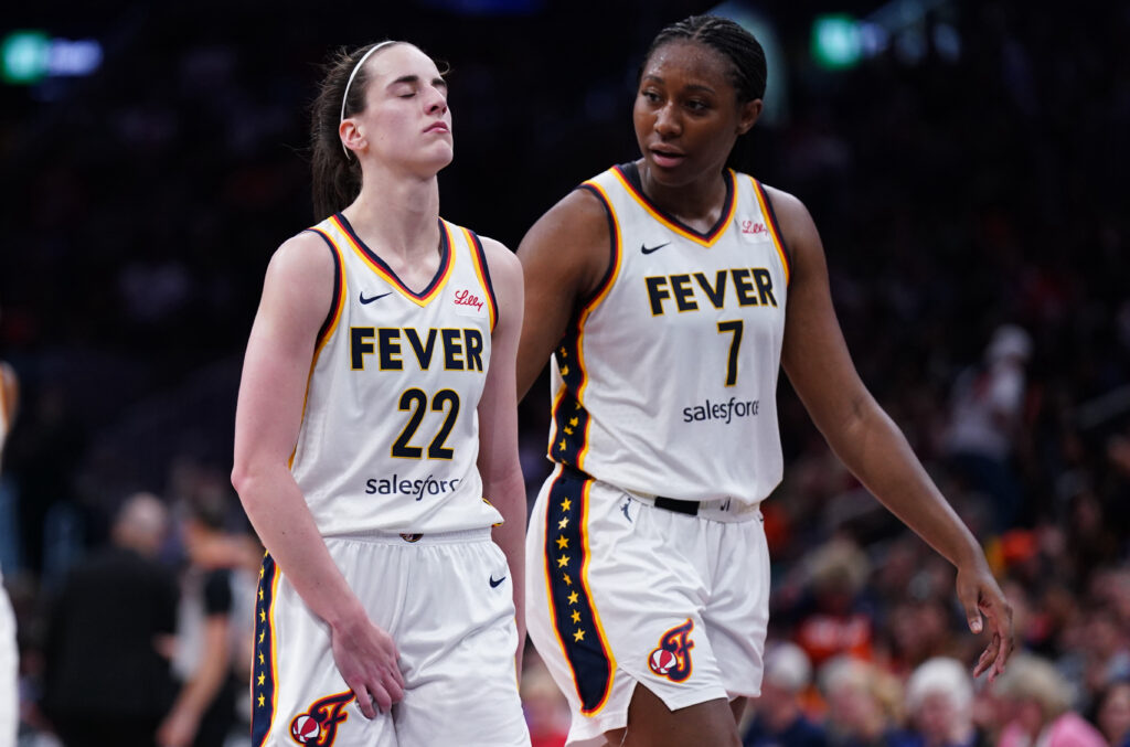 Indiana Fever star Caitlin Clark reacts to a possible re-injury as she exits a 2025 WNBA game next to teammate Aliyah Boston.