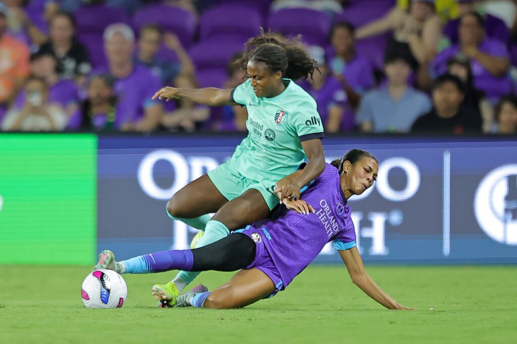 Orlando Pride forward Ally Watt slide tackles Kansas City Current forward Nichelle Prince during a 2025 NWSL match.
