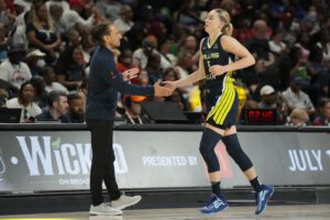 Dallas Wings rookie Paige Bueckers high-fives head coach Chris Koclanes during a 2025 WNBA game.