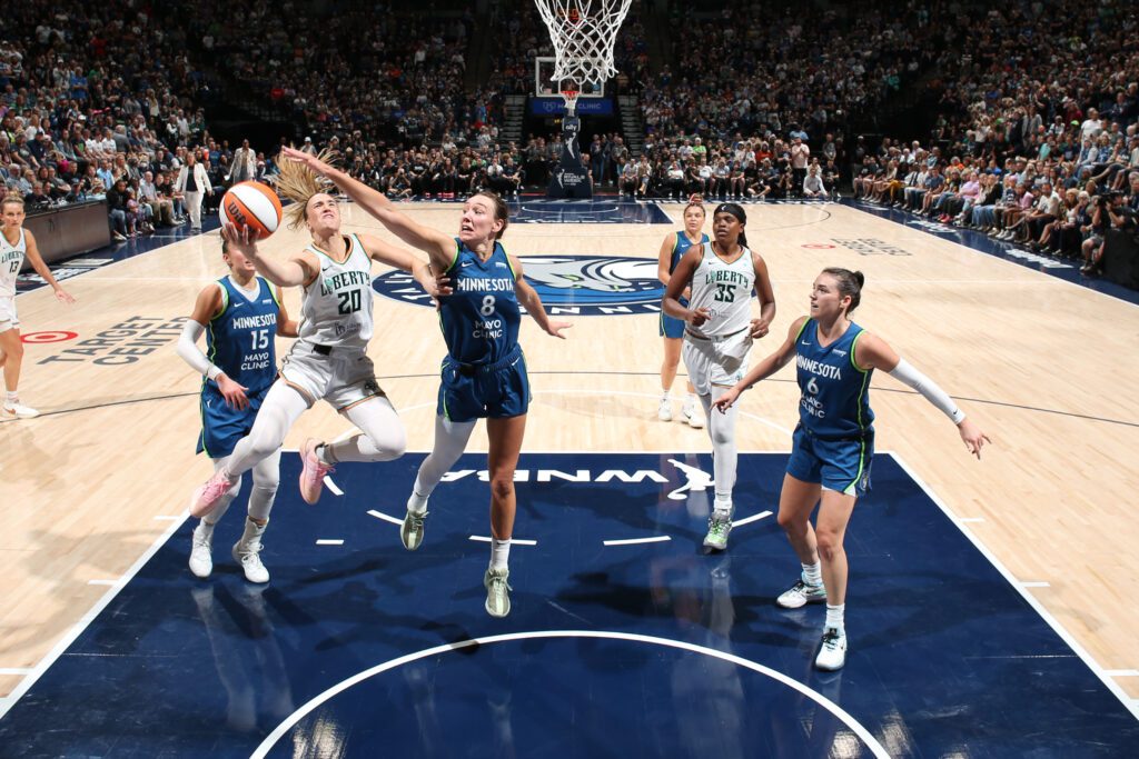 New York Liberty guard Sabrina Ionescu drives to the basket as Minnesota Lynx forward Alanna Smith tries to block her shot during a 2025 WNBA game.
