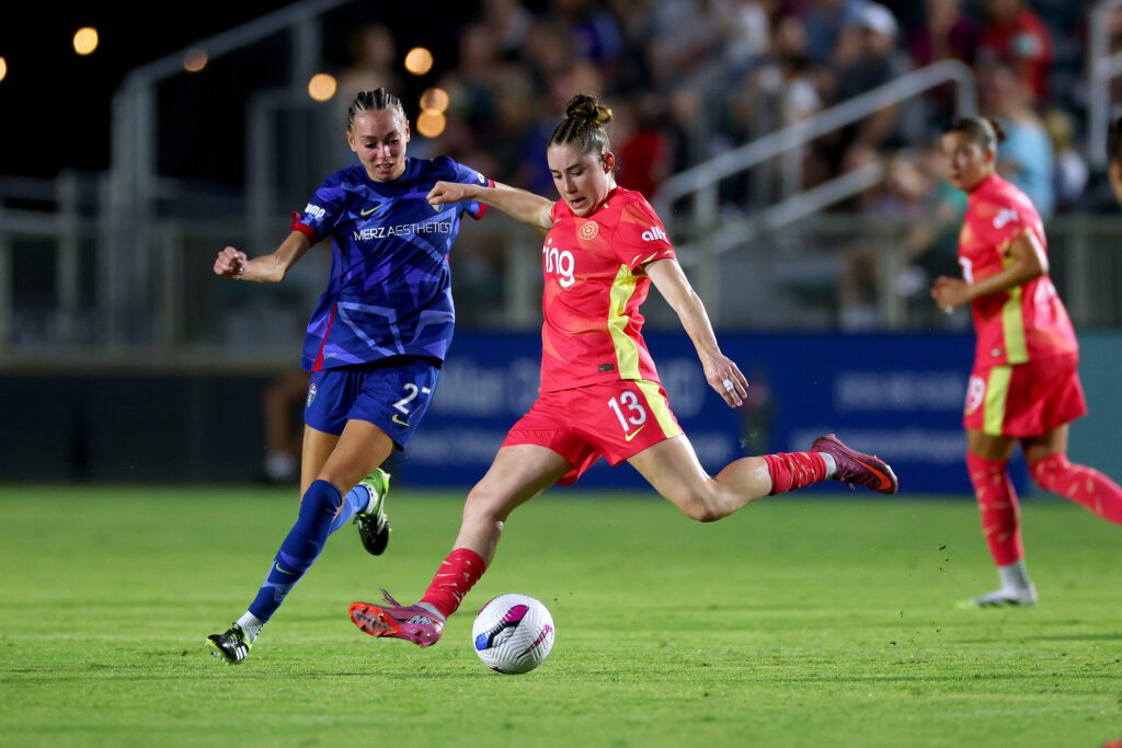 Portland Thorns midfielder Olivia Moultrie strikes the ball as North Carolina Courage defender Maycee Bell chases during a 2025 NWSL game.