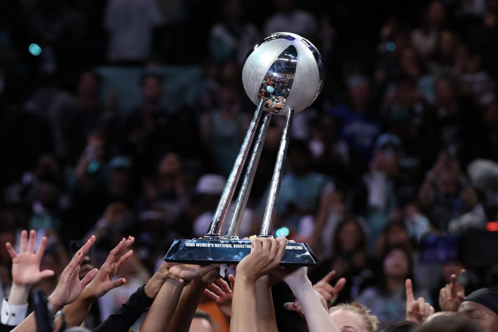 New York Liberty players lift the 2024 WNBA Championship trophy.