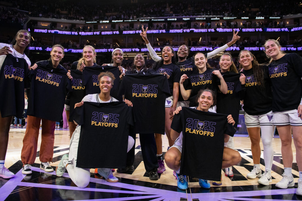 The Golden State Valkyries celebrate their postseason-clinching win while holding up "2025 WNBA Playoffs" T-shirts after a game.