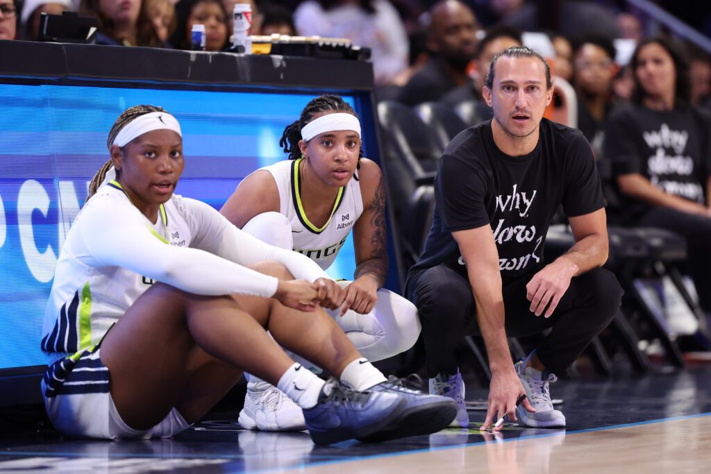 Dallas Wings forward Myisha Hines-Allen, guard Aziaha James, and head coach Chris Koclanes look on from the sideline during a 2025 WNBA game.