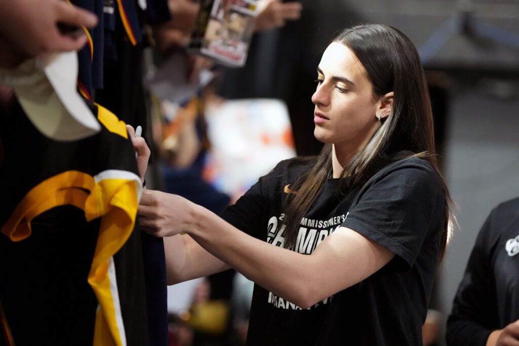 Indiana Fever star Caitlin Clark signs autographs before a 2025 WNBA game.