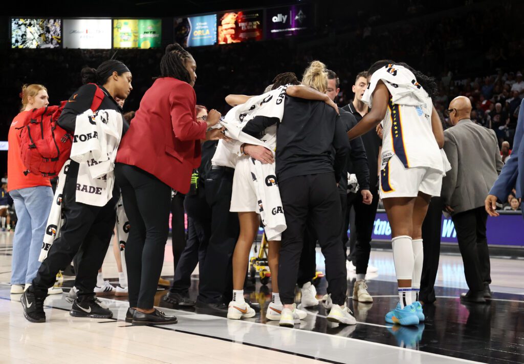 Indiana Fever medical and training staff help injured guard Kelsey Mitchell off the court during Game 5 of the 2025 WNBA semifinals.