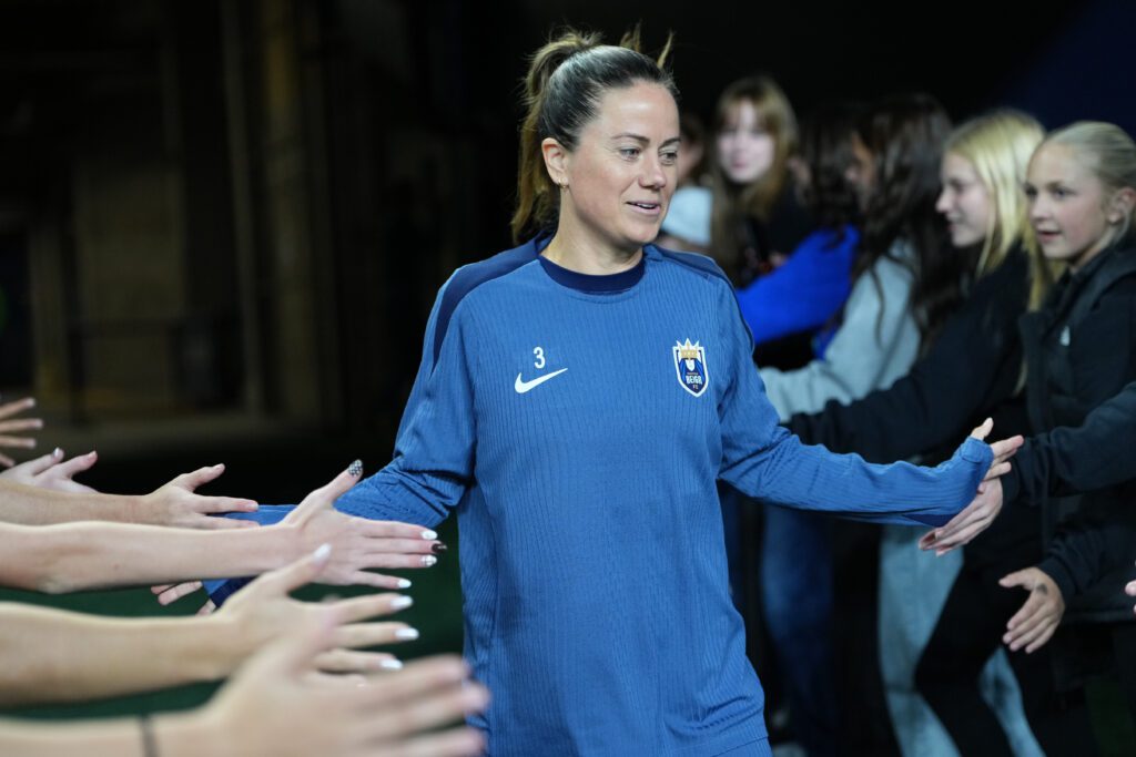 Seattle Reign defender Lauren Barnes gives high-fives to fans while entering the pitch to warm up for a 2025 NWSL match.