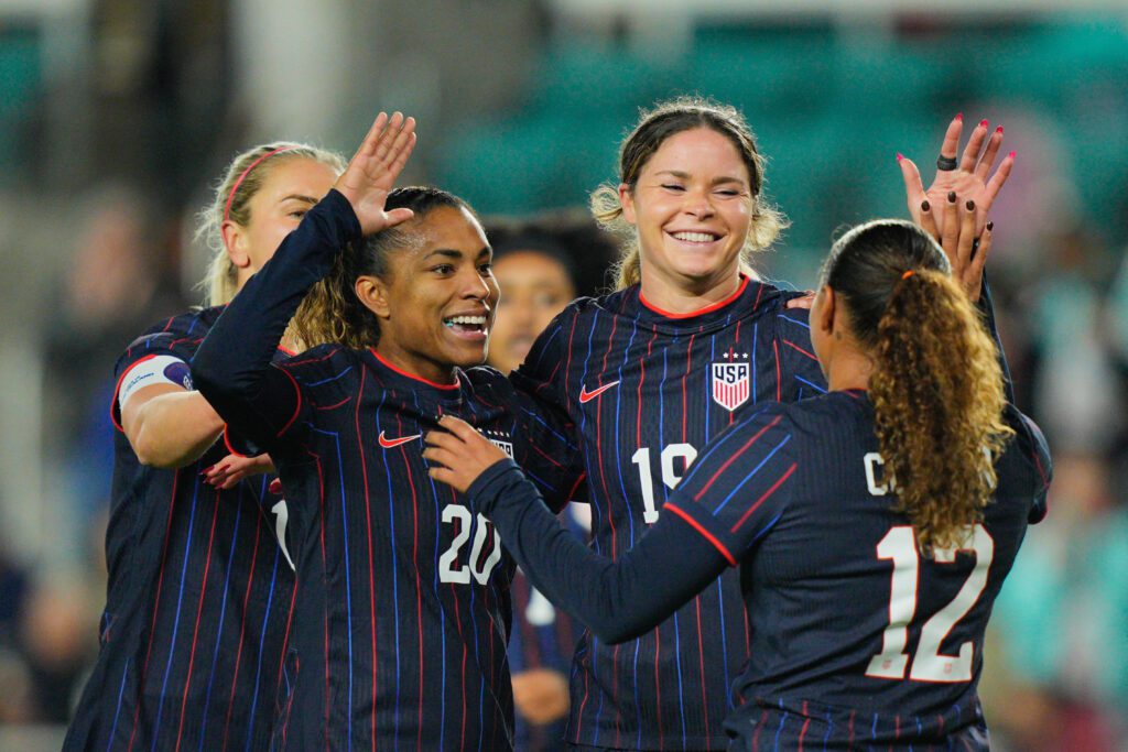 USWNT midfielder Catarina Macario and wingers Emma Sears and Michelle Cooper celebrate one of Sears's three goals during a 2025 friendly.