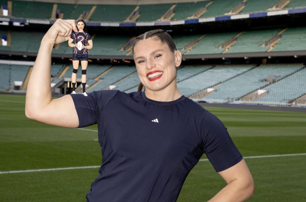 USA rugby star Ilona Maher poses holding her signature Barbie doll.