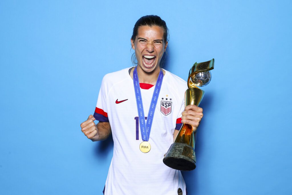 USWNT star Tobin Heath poses holding the 2019 World Cup trophy.