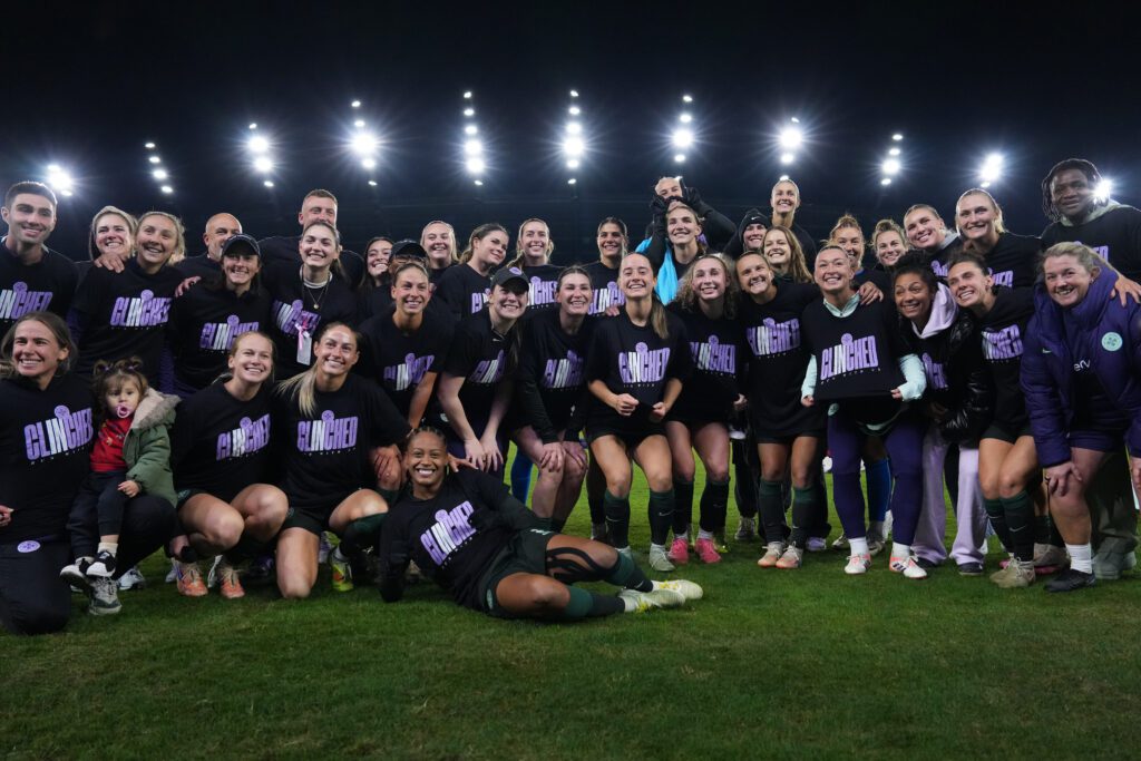 Racing Louisville players, coaches, and staff wear T-shirts that say "Clinched" after securing a franchise-first berth to the 2025 NWSL Playoffs.