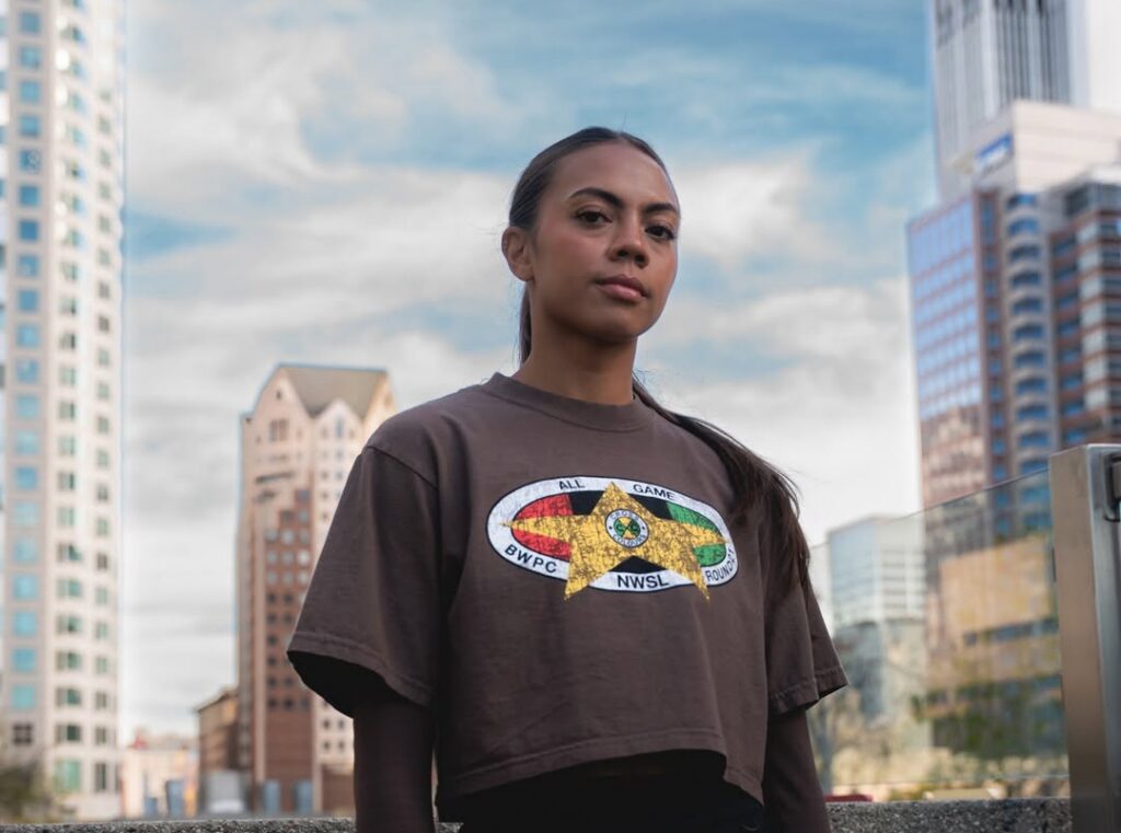 Denver Summitt forward Ally Brazier (née Watt) poses wearing a cropped T-shirt from the 2026 NWSL x BWPC Black History Month capsule collection.