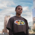 Denver Summitt forward Ally Brazier (née Watt) poses wearing a cropped T-shirt from the 2026 NWSL x BWPC Black History Month capsule collection.