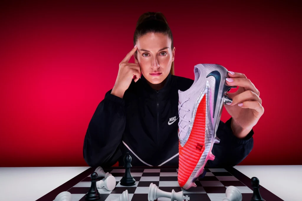 Spain soccer star Alexia Putellas poses over a chess board holding her Nike Player Edition Phantom 6 cleat