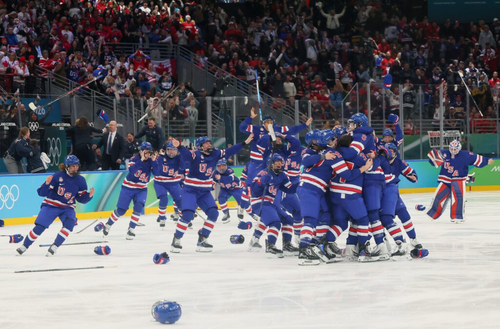 USA women's hockey players toss gloves and sticks into the air in celebration after winning gold at the 2026 Winter Olympics.