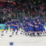 USA women's hockey players toss gloves and sticks into the air in celebration after winning gold at the 2026 Winter Olympics.