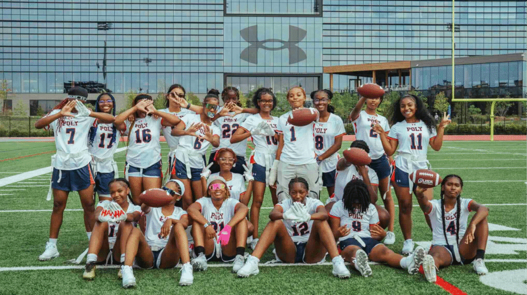 The Baltimore Polytechnic Institute girls varsity flag football team poses on the Under Armour Stadium field outside the sportswear company's Maryland headquarters.