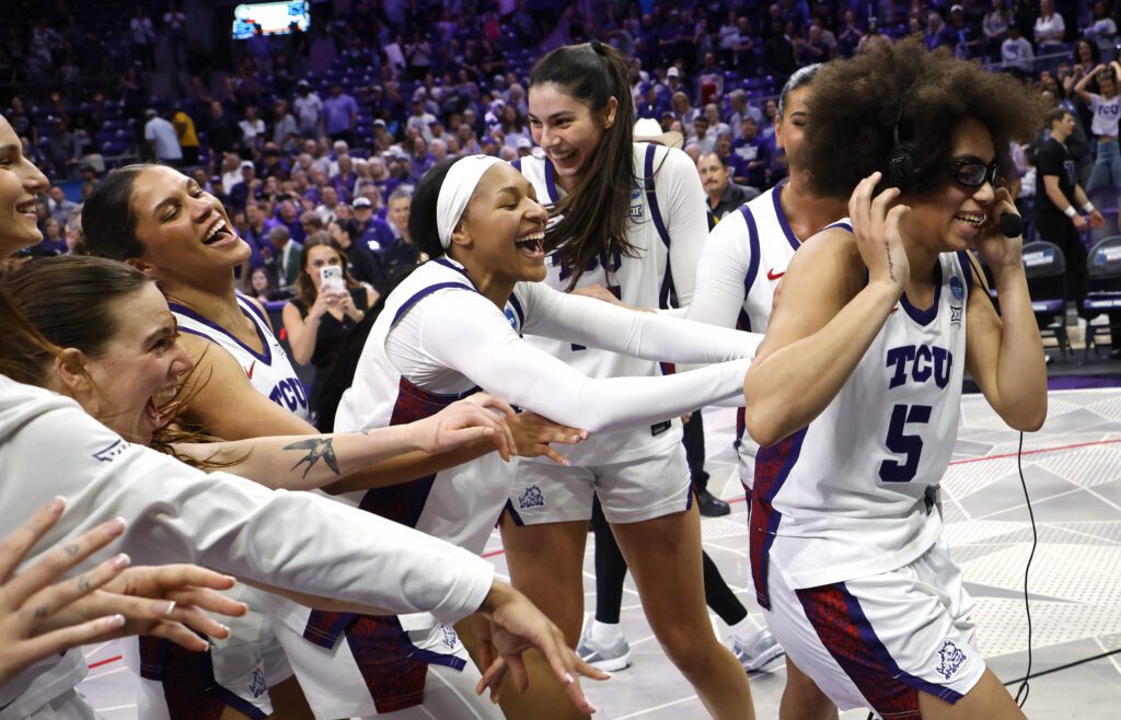 Guard Olivia Miles is mobbed by her TCU teammates during a TV interview as they celebrate their second-round win in the 2025/26 NCAA women's basketball tournament.